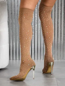 Close-up of shimmering rhinestone mesh over-the-knee stiletto boots.