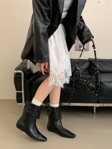 Stylish black leather ankle boots with a unique foldable collar design in a studio setting