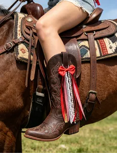 Close-up detail of a red polka dot bow ribbon charm for western cowboy boots on a horse