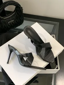 Nahaufnahme von eleganten schwarzen Stiletto-Mules mit Krokoprägung und Klarsichtriemen