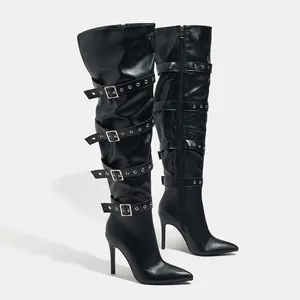 Detail view of black over-the-knee boots with stiletto heels and punk buckle straps.