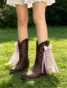 Detail view of pink and white ribbon bow decorations on brown western cowboy boots