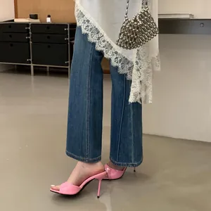 Pink patent leather stiletto mules styled with denim jeans for a chic fashion look.