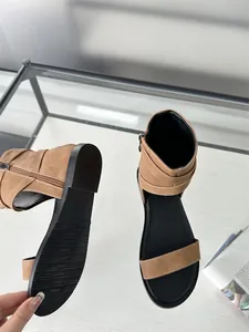 Close-up view of brown flat Roman sandals showing the black anti-slip rubber sole