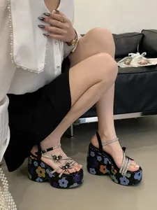 Detailed view of black platform wedge sandals with floral sequins and rhinestone butterflies