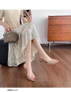 Model wearing elegant gold lace pointed-toe stiletto mules in a stylish interior