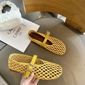 Detailed view of yellow hand-woven breathable Mary Jane flats with buckle strap on chair