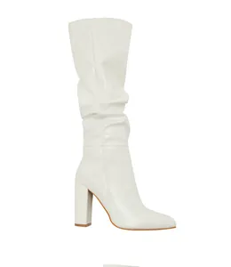 Detailed side view of a stylish white patent leather pointed toe ruched mid-calf boot.