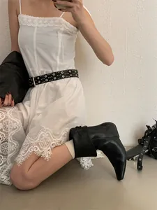 Model wearing black pointed-toe leather short boots with a stylish white lace dress