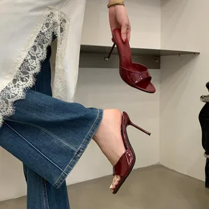 Close-up of red patent leather stiletto mule sandals with open toe design