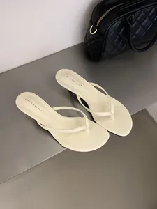 Primo piano di sandali infradito color crema con tacco basso e design elegante