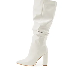 Stylish white patent leather slouchy knee-high boots with pointed toe and chunky heel.