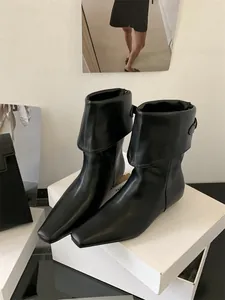 Detailed view of elegant black leather ankle boots with a unique fold-over cuff design