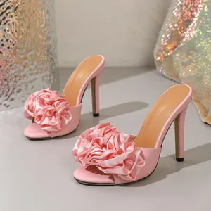 Close-up of pink high heel sandals featuring elegant oversized satin flower decorations.
