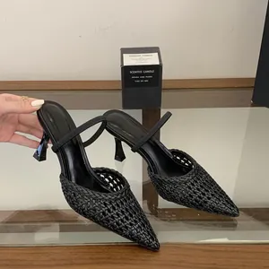 Detailed macro view of black woven pointed-toe high heel sandals with hollow mesh design.