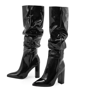 Close-up detail of black patent leather slouched mid-calf boots with block heels