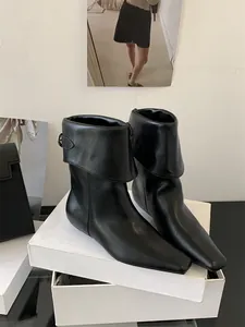 Detailed view of black leather ankle boots with a unique foldable cuff design