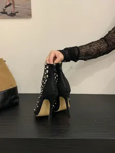 Macro detail showing the back zipper and silver spikes of black stiletto sandals.