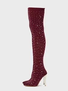 Detailed side view of burgundy rhinestone thigh high boots with gold stiletto heels.