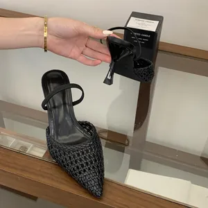 Close-up of black woven pointed-toe heeled sandals showing stiletto heel detail