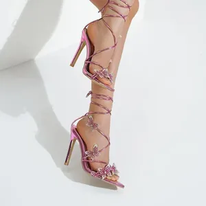 Detail van metallic roze veterschoenen met naaldhak en glinsterende vlinders van strass