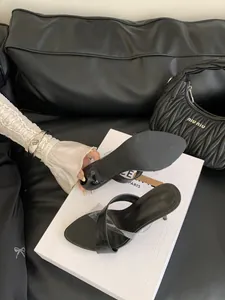 Nahaufnahme von schwarzen Pantoletten mit transparentem Riemen und Pfennigabsatz.