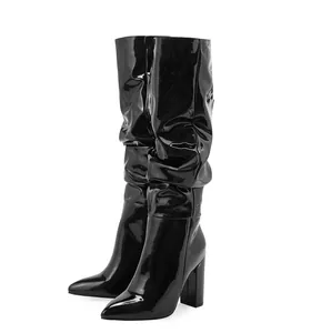 Detailed view of shiny black patent leather mid-calf slouch boots with block heel