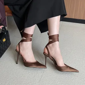 Elegantes tacones de satén marrón con correas en el tobillo y diseño de punta fina.
