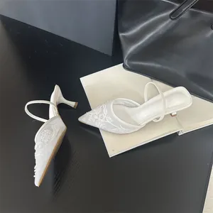 Detailed view of elegant white floral embroidery on mesh pointed-toe mule heels