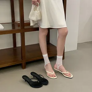 Eleganti sandali infradito bianchi con tacco basso in un ambiente minimalista