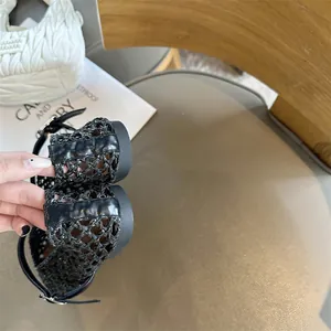 Close-up of black hand-woven mesh detail and flat sole of women's Mary Jane shoe
