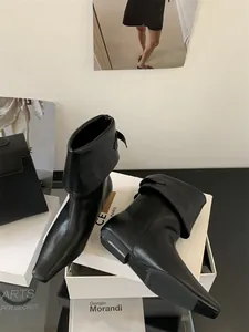 Detailed view of black leather ankle boots with convertible shaft and square toe