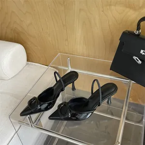 Detailed view of black patent leather pointed-toe pumps with a glossy square buckle