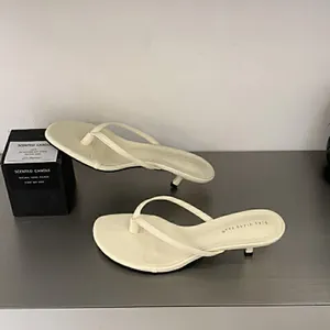 Eleganti infradito minimaliste color crema con tacco a rocchetto per un look chic.