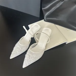 Detailed view of elegant white pointed-toe mesh mules featuring intricate floral embroidery