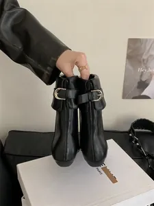 Elegant black leather Chelsea boots featuring a stylish metal buckle decoration
