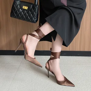 Elegantes tacones de aguja en satén marrón con punta fina y cintas para atar al tobillo