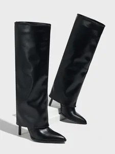 Detail von schwarzen Stiletto-Hosenbeinstiefeln mit spitzer Kappe und weitem Schaft.