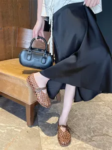 Detail view of woven brown Mary Jane flats with breathable hollow design on marble floor
