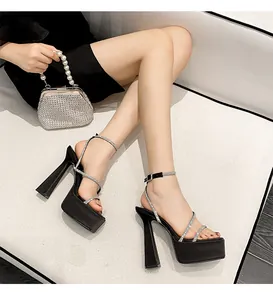 Model wearing black rhinestone platform sandals with chunky heels and silver clutch