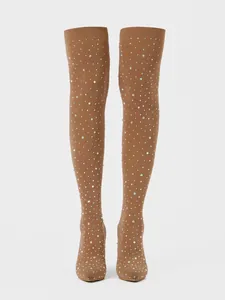 Detailed view of tan over-the-knee boots with dazzling rhinestones and sharp pointed toes