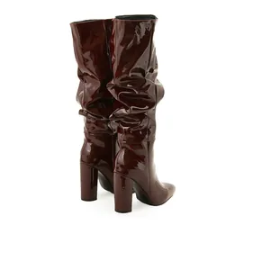 Detailed close-up of burgundy slouchy patent leather boots featuring pointed toe and block heel
