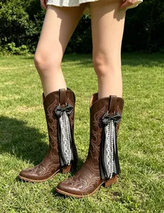 Detail view of black polka dot bow and lace ribbons on brown Western cowboy boots.