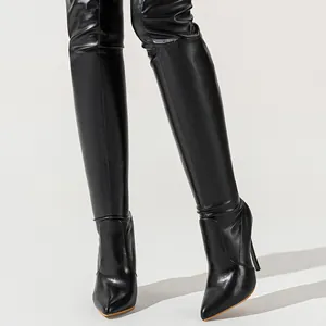 Detailed macro view of elegant black over-the-knee leather stiletto boots with pointed toe