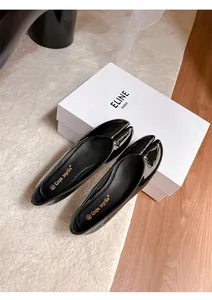 Close-up detail of black patent leather split-toe Tabi flats displayed on a luxury white shoe box