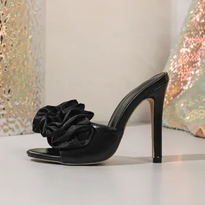 Side profile of elegant black stiletto high heel sandals with large flower detail