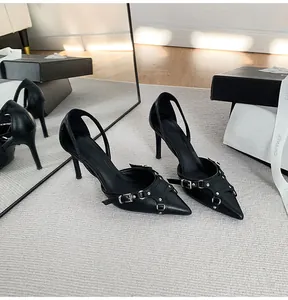Vista detallada de stilettos negros de punta con hebillas metálicas de estilo punk