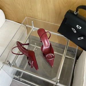 Elegant burgundy patent leather pointed-toe slingback heels with oval buckle on table