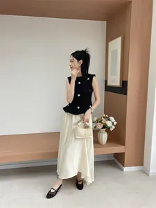 Detailed view of women's black embroidered mesh flat shoes worn with a cream skirt.
