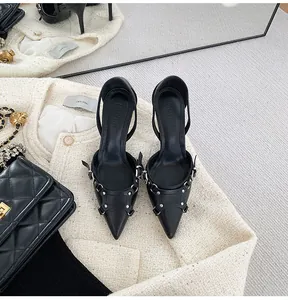 Primer plano de zapatos de tacón negro con punta y detalles de hebillas plateadas.